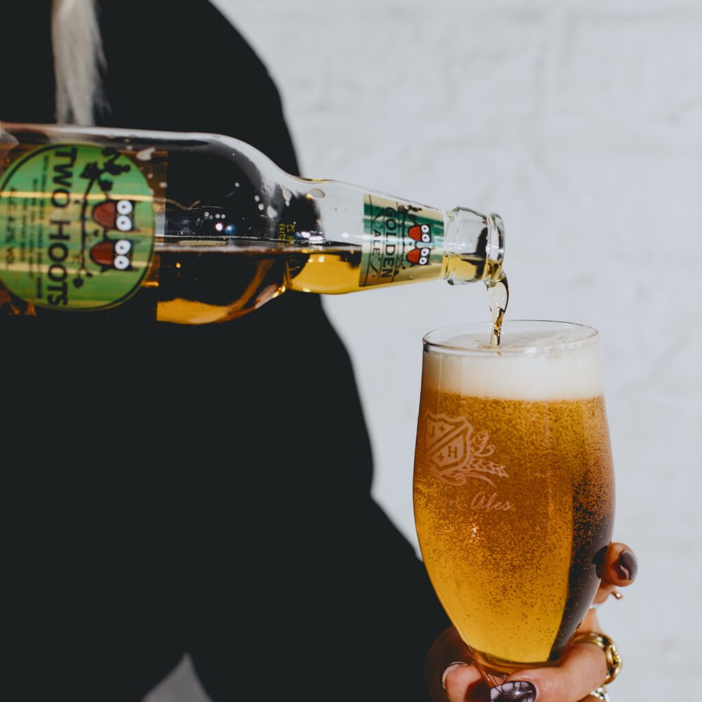 Two Hoots bottle pouring beer into a glass.