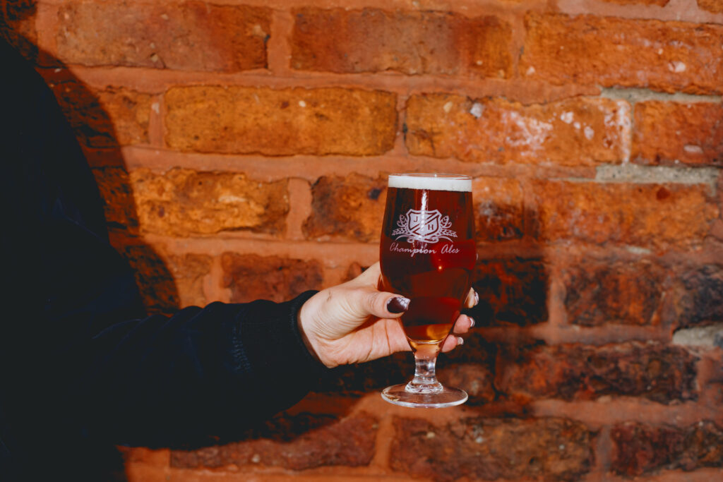 A woman holding a glass of Maple Moon Ale.