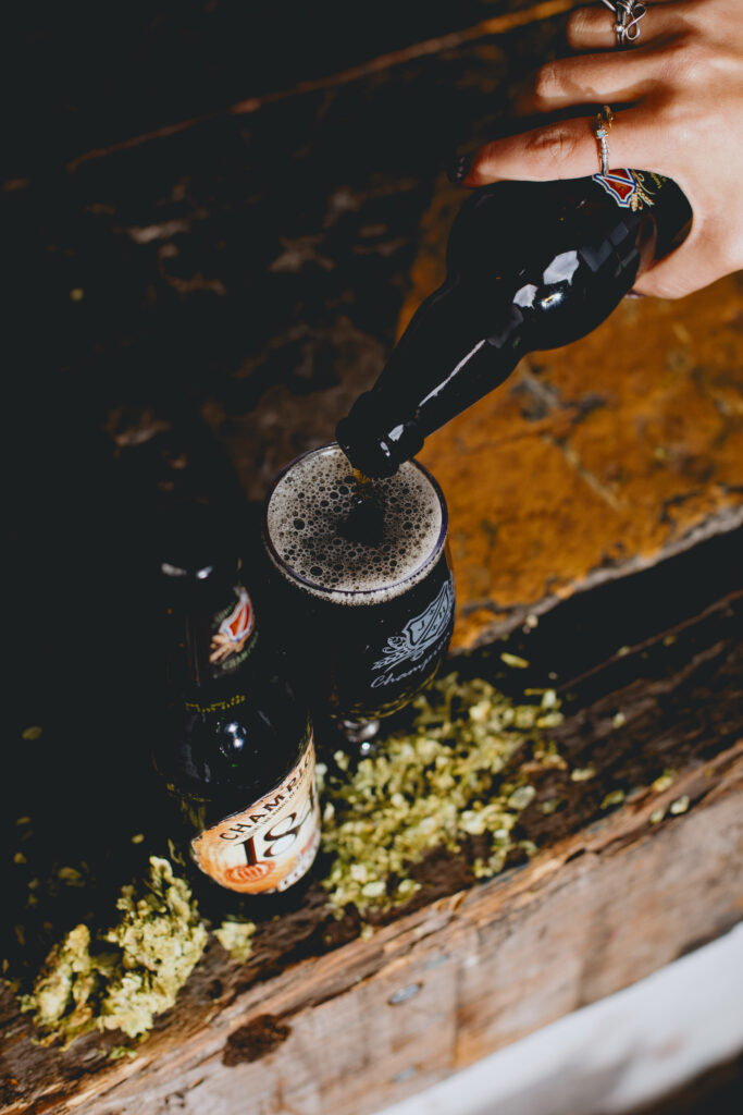 A woman's hand poring 1849 Champion Ale into a glass.