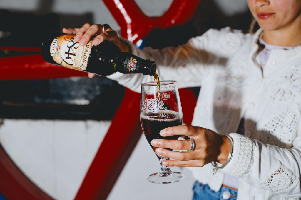 A woman poring 1849 Champion Ale into a glass.