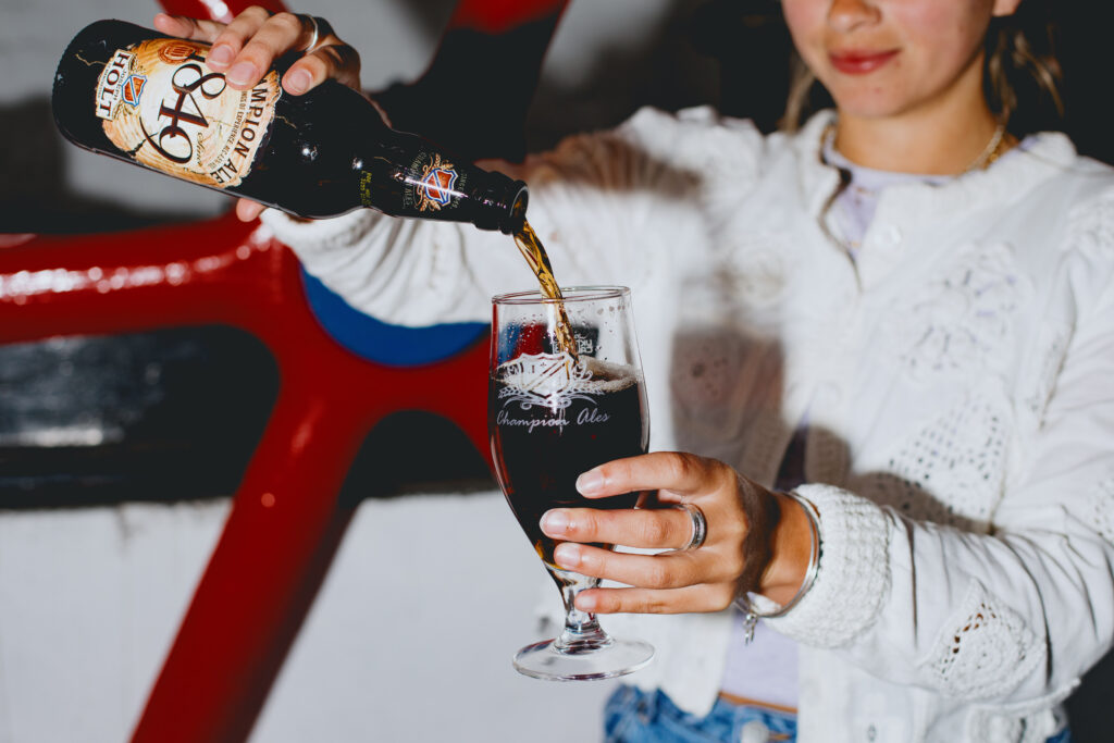 A woman poring 1849 Champion Ale into a glass.