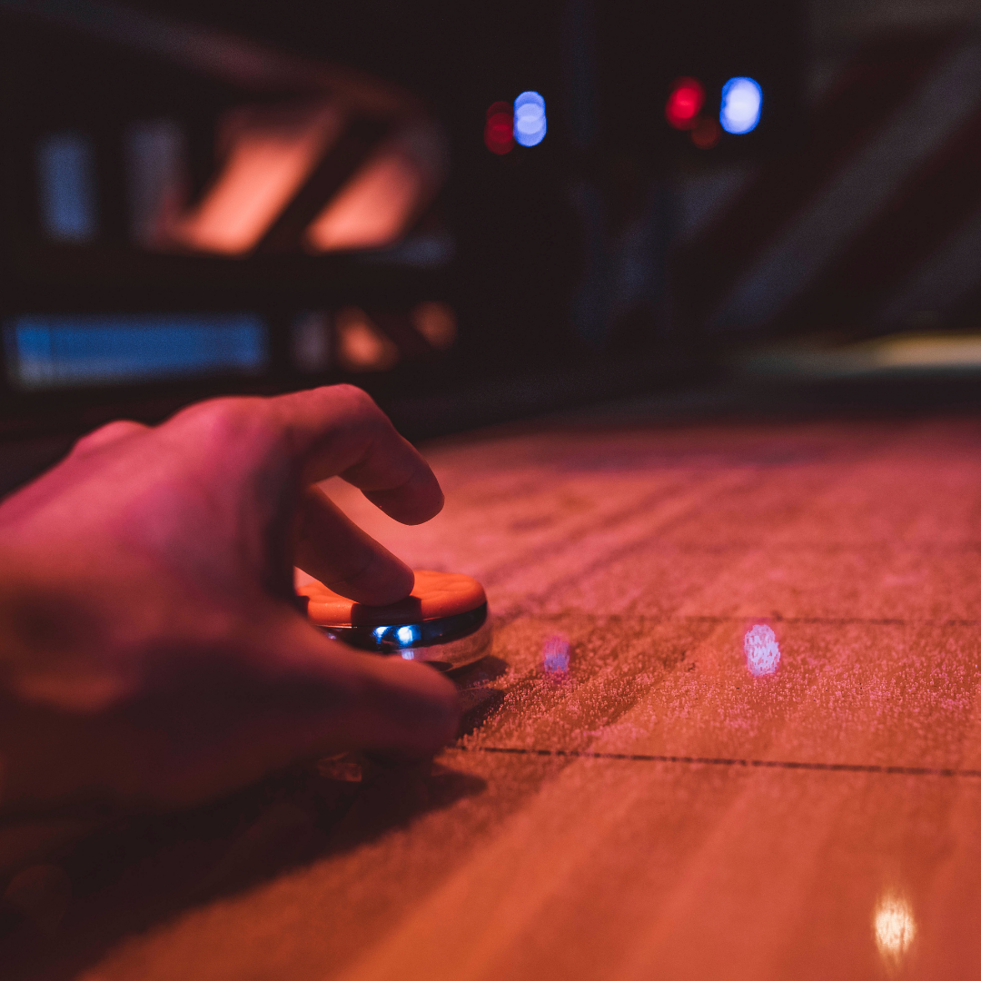 A hand siding puks on a shuffleboard