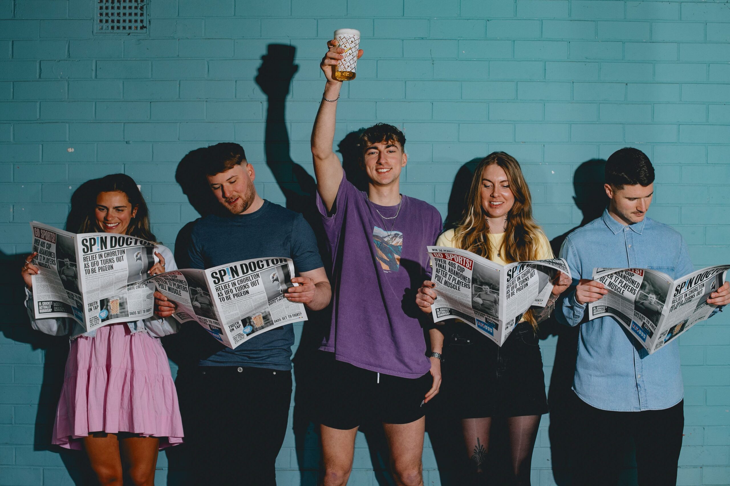 Five people stood in a line against a blue wall