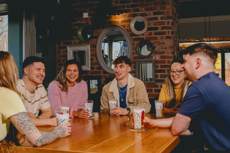 A group playing Monopoly round a table drinking beer